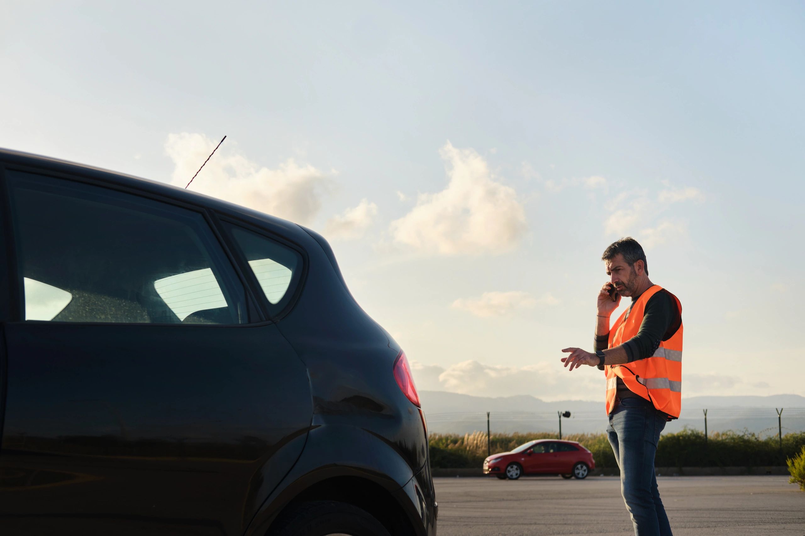 Driver on the phone beside a disabled vehicle waiting for locksmith help